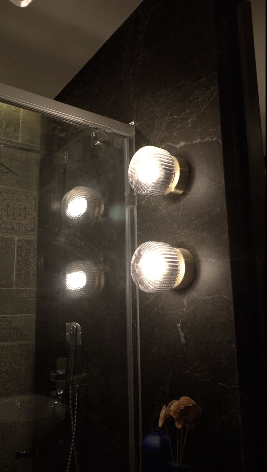 Samsara Residence bathroom with brass sconces on dark stone
